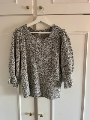 Svartvit stickad tröja med puffärm - Mysig stickad tröja i svartvitt melerat garn med rund halsringning och puffiga trekvartsärmar. Tröjan har ribbade muddar vid ärmslut och nederkant, perfekt för en avslappnad och trendig look.💞💞köpte på arkivet men är från Coster Copenhagen för 450 kr men säljer för 200!
