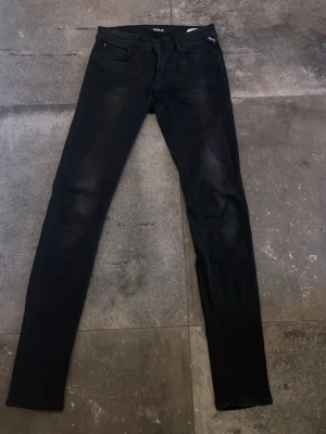 Svarta skinny jeans från Replay - Snygga svarta skinny jeans från Replay med klassisk femficksdesign och låg midja. Jeansen har en stilren look och är tillverkade i stretchigt denim för en bekväm passform. Perfekta för dig som gillar en smal siluett och tidlös stil.