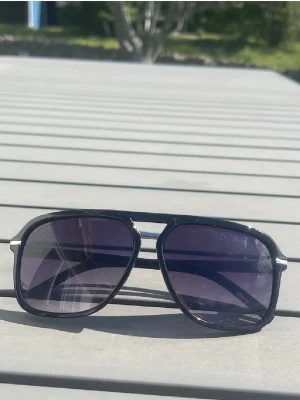Svarta pilotbågar solglasögon - Snygga solglasögon med svarta pilotbågar och mörka glas. Klassisk design med metalliga detaljer vid skalmarna. Perfekta för att ge en cool vibe till din outfit i sommar.