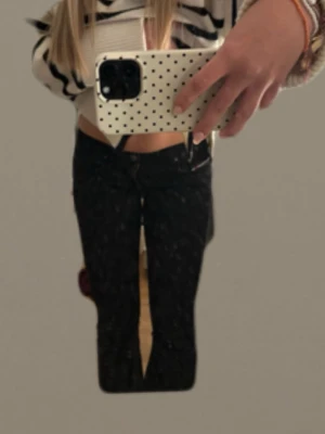 Svarta bootcut jeans - Säljer ett par svarta bootcut jeans med klassisk femficksdesign och knappgylf. Jeansen har en något utsvängd passform nedtill och sitter snyggt i midjan. Perfekta till en trendig vardagslook. Säljer då de börjar bli för små o midjan (midjemått 68). Passar dunder i längden och jag är 166! Dom är sydda bootcut men de syns inte!💓
