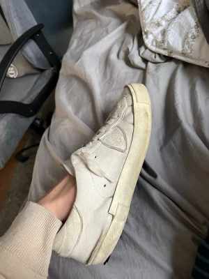 Vita sneakers från Philippe Model - Snygga vita sneakers från Philippe Model med klassisk låg siluett. Skorna har ovandel i läder, vita skosnören och diskret logga på sidan. Yttersulan är vit med en något vintage look. Perfekta för en clean och stilren outfit.