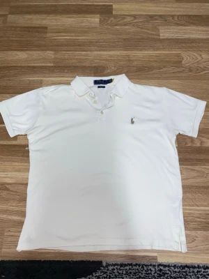 ÄKTA Polo Ralph Lauren – Slim fit - Klassisk vit pikétröja från Polo Ralph Lauren i slim fit-modell. Tröjan har krage, knappar framtill och den ikoniska broderade polospelaren på bröstet. Perfekt för en stilren och tidlös look.