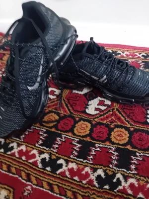 Nike Air Vapormax svarta sneakers - Snygga Nike Air Vapormax sneakers i svart med reflekterande detaljer och stickad ovandel. Skorna har en tydlig Nike-logga på sidan och en unik sula med synliga luftbubblor för extra komfort. Perfekta för dig som gillar sportig och modern stil.