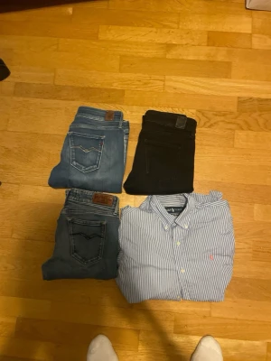 Två blå jeans och ett par svarta jeans - Säljer två par blå jeans och ett par svarta jeans. De blå jeansen har klassisk femficksdesign och snygga sömmar på bakfickorna. De svarta jeansen är stilrena och passar till det mesta. Alla byxor är i jeansmaterial och har normal passform.