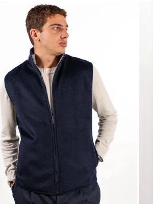 Ull väst ifrån sothiares - Vår marinblå vändbara ullväst kombinerar stil och funktionalitet med sin rena design och genomtänkta funktioner. Denna väst erbjuder inte bara två stilar i ett, utan garanterar också en elegant silhuett. Oavsett om den bärs som ett lager-på-lager-plagg under en kappa under kallare årstider eller som ett fristående ytterplagg, är denna vändbara ullväst ett mångsidigt och oumbärligt tillskott till vilken garderob som helst. Perfekt för kallare årstider. Nypris 1400kr