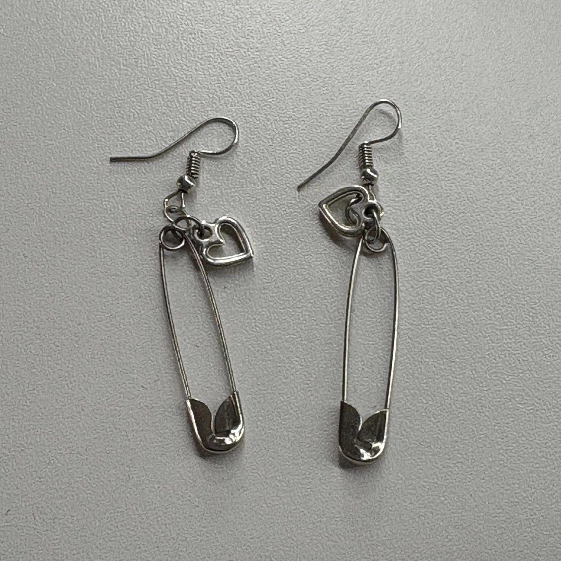 Silvriga örhängen med säkerhetsnål och hjärta