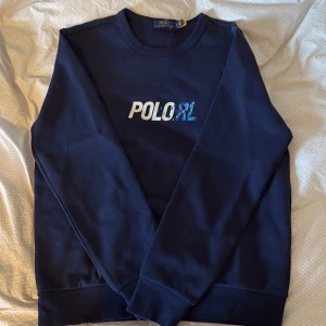 Mörkblå sweatshirt från Polo Ralph Lauren - Snygg mörkblå sweatshirt från Polo Ralph Lauren sweatshirt med tryck på bröstet. Väldigt simpel och fin tröja. Storlek medium. Tröjan är näst intill aldrig använd! Hör av er för fler frågor Mvh Vincent 