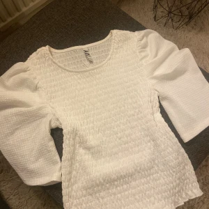 Vit blus med puffärmar från JDY - Väldigt fin vit blus från JDY med puffiga trekvartsärmar och smockad struktur. Storlek Xs.