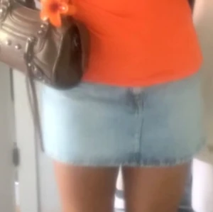 Ljusblå jeanskjol i klassisk modell - Säljer en ljusblå jeanskjol i klassisk femficksmodell med bälteshällor och dragkedja fram. Kjolen är kort och har en rak passform, perfekt till sneakers eller boots. Materialet är bomull och den har en snygg tvättad denimlook.