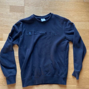 Svart sweatshirt från Champion - Svart sweatshirt från Champion med broderad logga framtill. Tröjan är i bra skick . Skriv vid funderingar!