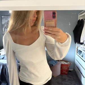 Vit ribbad topp med puffärm - Säljer en vit ribbad topp med långa puffärmar och snygg v-ringad halsringning.  Sparsamt använd inga tecken, normal i storlek och jätte skönt tyg. 