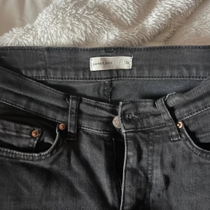 Svarta bootcut jeans  - Svarta jeans från  Gina Tricot i sorlex 34 (XS) . Byxorna har bootcut-ben och normal passform, med snygga kopparfärgade nitar och knapp. Tillverkade i stretchig denim för extra komfort. Använda men i fint skick, har en liten slitning längst ner på byxorna vid hälen.