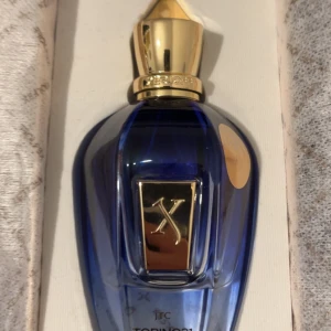 Xerjoff lyxig parfymflaska i box - Exklusiv parfym från Xerjoff i elegant blå flaska med gulddetaljer. Levereras i originalförpackning, perfekt för dig som vill sticka ut med något unikt och lyxigt. Modellnamnet Torino21 syns på flaskan.