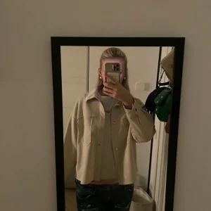 Beige overshirt från Zara - Snygg beige overshirt från Zara med klassisk krage och två bröstfickor. Jackan har knappar framtill och är i ett mjukt material som känns skönt mot huden. Perfekt att slänga över en hoodie eller t-shirt. Säljer pga den inte används längre, skriv vid frågor eller intresse 🥰