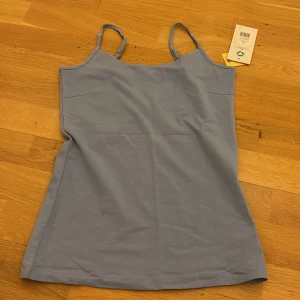 Ljusblå linnetopp med smala axelband - Ljusblå linnetopp med smala axelband. Dubbeltyg vid bröstet så man inte behöver andvända bh. St S