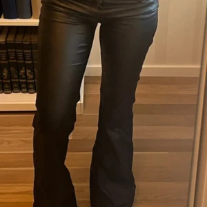 Svarta bootcut byxor i skinnimitation - Snygga svarta byxor med bootcut passform och lätt glansig yta som ger en cool skinnlook. Inte mina bilder men om de är några funderingar är det bara att skriva! Storlek S