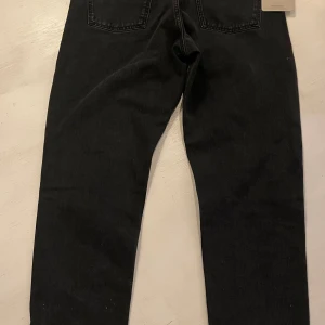 Carhartt WIP Newel Pant svarta jeans - Svarta Carhartt WIP Newel Pant jeans med relaxed tapered fit och regular waist, stone washed denim. Oanvända.