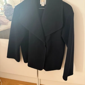 Marinblå cardigan jacka från Gina Tricot - Marinblå cardigan jacka från Gina Tricot med bred krage och lång ärm. Jackan har en stilren och enkel design med mjukt stickat material som gör den skön att bära. Perfekt att slänga på sig när det är lite kyligt ute.