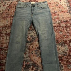 Ljusblå jeans  - Snygga ljusblå jeans med klassisk femficksdesign och raka ben. Jeansen har normal passform och är tillverkade i mjukt denimtyg med subtila slitningar framtill. Perfekt för dig som gillar en avslappnad och stilren look. O känt märke inte från Jack and Jones