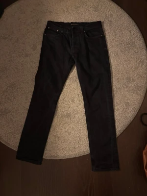 Svarta jeans från Nudie Jeans - Säljer ett par svarta nudie jeans i modellen grim trim. Storleken är W34 L34, och de har inga märkbara defekter. Hör gärna av er vid diskussioner kring pris eller andra funderingar.