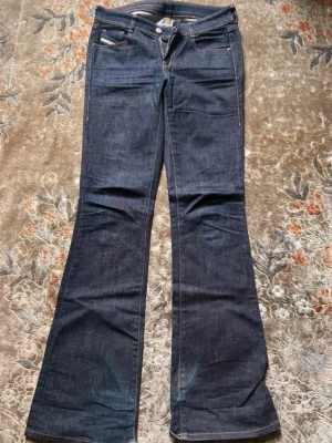 Mörkblå bootcut jeans från Diesel - Säljer ett par mörkblå bootcut jeans från Diesel. Mid waist, långa (passar mig som är 175) supersnygga, tyvärr förstörda nere.