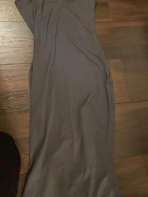 Mörkgrå långklänning - Säljer en stilren mörkgrå långklänning med enkel design och mjukt fall från shein. Klänningen har en rak siluett och är ärmlös, perfekt för dig som gillar minimalistisk stil. Materialet känns lent och följsamt mot kroppen.