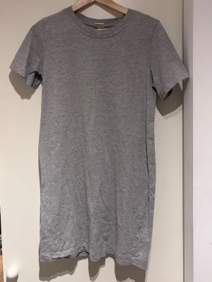 T-Shirt dress - Säljer denna gråa T-Shirt dressen från H&M. Ger en casual look och passar perfekt att ha till sneakers på sommaren eller att sova i. Aldrig använd. 