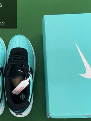 Nike Air Force 1 Tiffany & Co sneakers - Nike Air Force 1 sneakers i samarbete med Tiffany & Co. Skorna har en ljus turkosblå färg med svarta detaljer och vit sula. Swoosh-loggan är svart och bak på hälen finns en silverplatta med Tiffany & Co. Broderad Nike Air-logga i blått på hälen. Tillverkade i skinn med snörning.  UTAN BOX