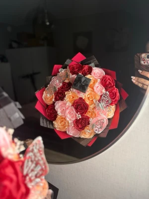 Mix bukett  - Bilderna visar en bukett med konstgjorda rosor i rött, rosa och aprikos, dekorerad med fjärilar och en liten svart ask. 