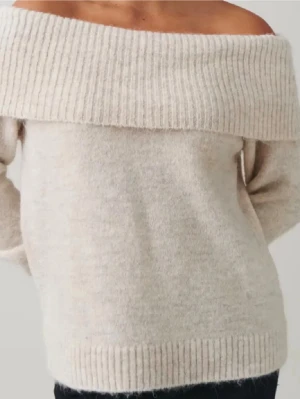 Beige offshoulder stickad tröja - Superfin beige stickad tröja med bred ribbad offshoulder-krage. Mjuk och skön, perfekt för lager-på-lager och chill höst- eller vinterstil. Långärmad och loose fit för en avslappnad vibe. Storlek 170 men skulle säga den passar S-XS