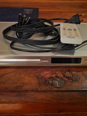 Philips DVP3172 DVD Player - Philips DVP3172 DVD-spelare i gott skick, komplett med fjärrkontroll och anslutningskablar. Enheten har SCART och RCA-utgångar, perfekt för filmkvällar. Inga synliga defekter eller större slitage. Enkel att använda och passar de flesta TV-apparater.