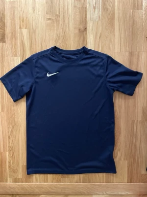 Nike t-shirt  - En klassisk marinblå tränings t-shirt från Nike i storlek: 158-170 cm . Tröjan är perfekt för träning. 