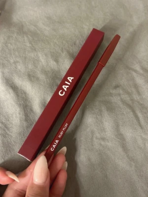 CAIA läppenna Ruby Plum - Snygg läppenna från CAIA i färgen Ruby Plum. Pennan har en djup plommonröd nyans och kommer i en stilren, matt vinröd förpackning. Perfekt för att definiera och forma läpparna med precision. Pennan är i klassisk trädesign med skruvlock.