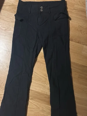 Svarta kostymbyxor med fickor - Säljer mina svarta kostymbyxor/halvcargo byxor. Rak passform och sitter riktigt fint. 
