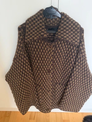 Zara Jacka - Snygg kappa från Zara i brunt och beige med rutigt mönster. Kappan har stora knappar framtill, bred krage och en loose passform. Perfekt för dig som vill sticka ut med en unik och trendig look.