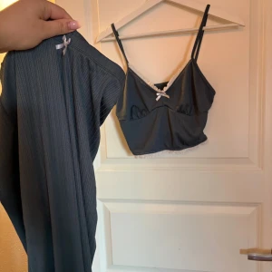 Grått ribbat underklädesset med spets - Säljer ett grått underklädesset med ribbad struktur. Setet består av en långärmad body och en matchande bh-topp med smala axelband. Båda delarna har vita spetsdetaljer och en liten rosett framtill. Perfekt för dig som gillar en enkel men söt stil. Pyjamas från shein 