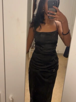 Bubbleroom Svart långklänning/ Balklänning med öppen rygg  - Säljer en elegant svart långklänning med smala axelband och rak halsringning, samt öppen rygg. Endast använd en gång på min bal men har inte kommit till användning efter de. Inga defekter på klänningen! 