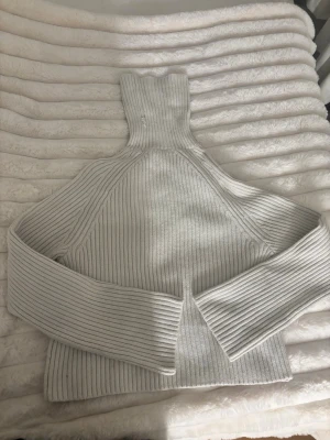 Vit ribbstickad polotröja - Säljer en stilren vit ribbstickad polotröja med höga muddar och lång ärm. Tröjan har en hög polokrage och är gjord i ett mjukt, tjockt material som håller dig varm. Perfekt för lager på lager och enkel att matcha med jeans eller kjol.från hm i stl xs