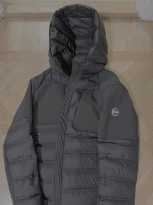 Svart dunjacka med huva från Colmar - Snygg svart dunjacka från Colmar med huva och quiltad design. Jackan har en diskret logga på ärmen, dragkedja framtill och långa ärmar. Perfekt för kalla dagar och har en modern, sportig look.     Nypris: 5599 den är använd under förra vintern endast efter jul. Helt ny fast använd några gånger