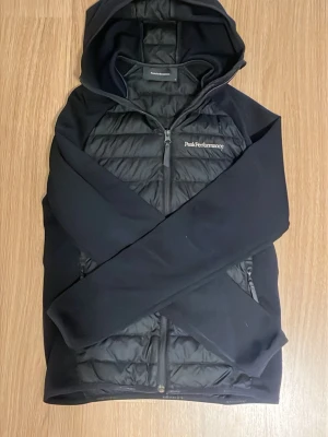 Svart cardigan jacka Peak Performance - Svart cardigan jacka från Peak Performance med huva och dragkedja framtill. Storlek S. Passar runt dig som är 175. Skriv om ni har några funderingar👍