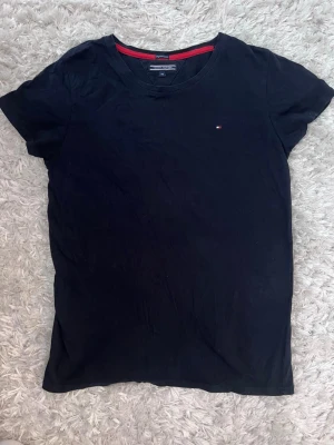 Mörkblå  t-shirt från Tommy Hilfiger - Klassisk svart t-shirt från Tommy Hilfiger med liten broderad logga på bröstet. T-shirten har rund halsringning och korta ärmar. Perfekt basplagg i mjuk bomull med diskreta detaljer och en clean look.