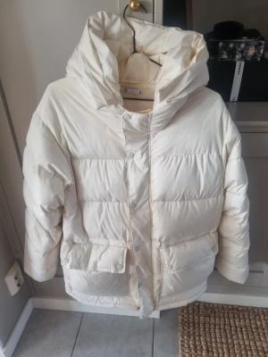 Vit dunjacka från Wakakuu xs - Säljer en fluffig vit dunjacka från Wakakuu i storlek XS. Passar även S. Jackan har stor huva, två stora fickor framtill med lock och tryckknappar samt dragkedja och tryckknappar hela vägen. Perfekt för kalla dagar och riktigt mysig att bära. Tvättas innan leverans. Nypris 4500:-