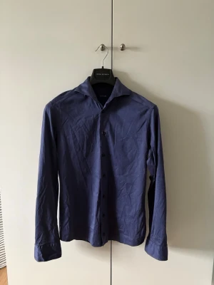 Blå Eton skjorta - Blå Eton skjorta i storleken S slim fit. Skjortan är i mycket bra skick, och stryker självklart den innan frakt! Säljes då den är för liten.