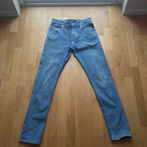 Blå Replay jeans straight fit - Säljer ett par klassiska blå jeans från Replay, modell MICKYM. Jeansen har en rak passform och normal midja. Tillverkade i mjukt bomullsmaterial med fem fickor och knappgylf. Perfekta för en avslappnad och stilren look.