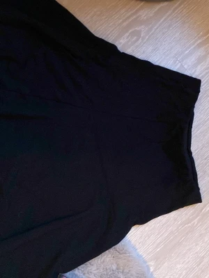 Svart långkjol från Lindex - En svart långkjol från Lindex med enkel och stilren design. Kjolen har en bred resår i midjan för skön passform och är gjord i ett mjukt material som faller snyggt. Perfekt att matcha med en crop top eller stickad tröja.