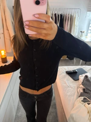 Svart croppad kofta med knappar - Säljer en svart croppad kofta med långa ärmar och knappar hela vägen framtill. Enkel och stilren modell som är lätt att matcha till olika outfits. 