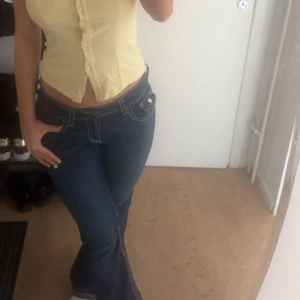 Mörkblå bootcut jeans med kontrastsömmar - Snygga mörkblå jeans med bootcut-modell och vita kontrastsömmar. Byxorna har låg midja och klassisk femficksdesign. Perfekta för dig som gillar en retro vibe och vill ha ett par jeans som sticker ut lite extra. Storlek 170