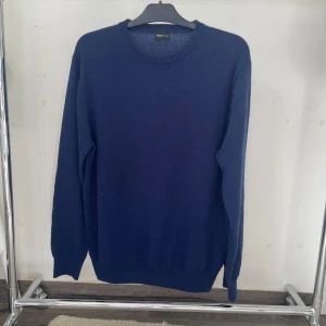 Mörkblå merinoulltröja från Swedish Fashion - Säljer en stilren mörkblå stickad tröja från Swedish Fashion i storlek L men sitter som en M. Tröjan är gjord av 90% merinoull och 10% kashmir, vilket gör den supermjuk och skön. Klassisk rund halsringning och långa ärmar, perfekt för kyliga dagar.