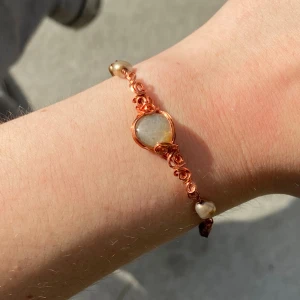 Handgjort koppararmband med pärlor - Unikt armband i koppar med snirkliga detaljer och pärlor i grått och vitt. Stenen i mitten har en mjuk rund form och armbandet har justerbar längd med små pärlor längs kedjan. Perfekt för dig som gillar boho och handgjorda smycken.