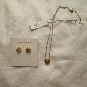 Tory Burch örhängen och halsband guld - Säljer två par snygga Tory Burch örhängen och ett matchande halsband i guld. Örhängena ligger runt 1000kr och halsbandet runt 1300kr. Dem är aldrig använda. 